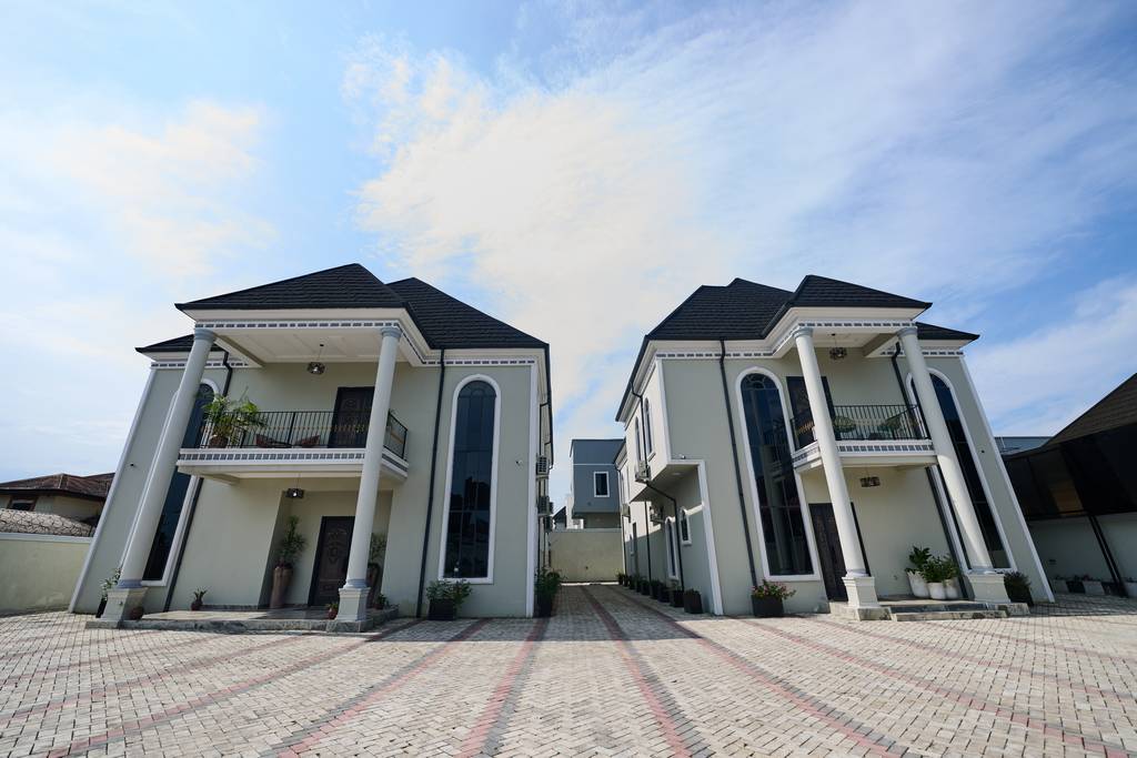 The 1% Manor: twin lodges with white columns and a paved courtyard in GRA Phase 1, Port Harcourt